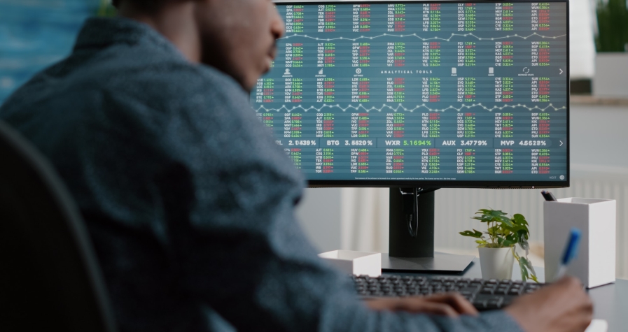 African american man looking into crypto currency stock markets trading checking stock ticker index